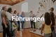 Verschiedene Menschen in einem Ausstellungsraum vor einem Objekt